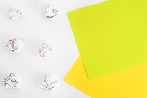 Overhead shot of crumpled paper in oder and colored flat sheets\
of paper on white background. zero waste concept