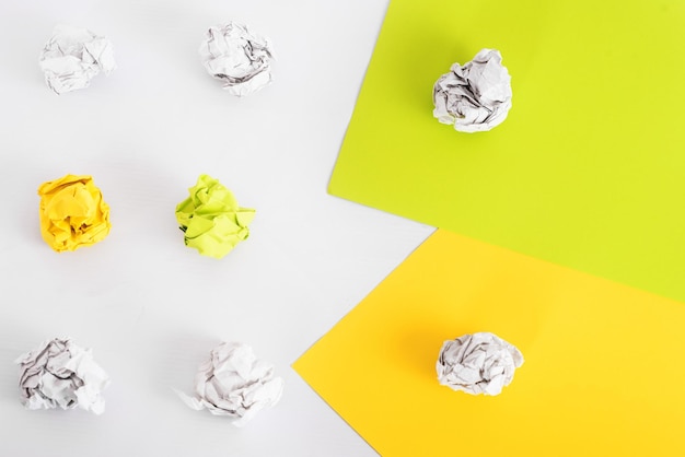 Overhead shot of crumpled paper in oder and colored flat sheets\
of paper on white background. zero waste concept