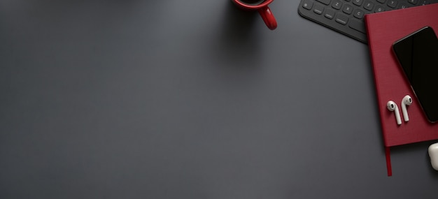 Overhead shot of dark luxury workspace with red notebooks and copy space with office supplies