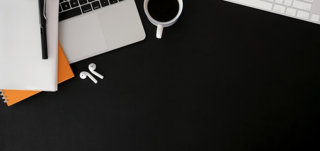 Overhead shot of dark trendy workplace with laptop computer and office supplies on black table