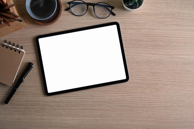 나무 책상에 디지털 태블릿 커피 컵 노트북과 안경을 쓴 디자이너 작업장의 오버헤드 샷