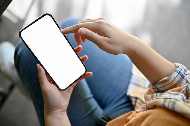 Foto overhead shot een vrouwelijke hand met een mockup met een wit scherm van een smartphone over haar schoot