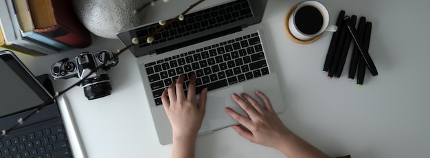 Overhead shot of female freelancer typing on laptop on white worktable