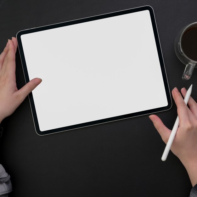 Photo overhead shot of female freelancer working on blank screen tablet  at dark modern workspace