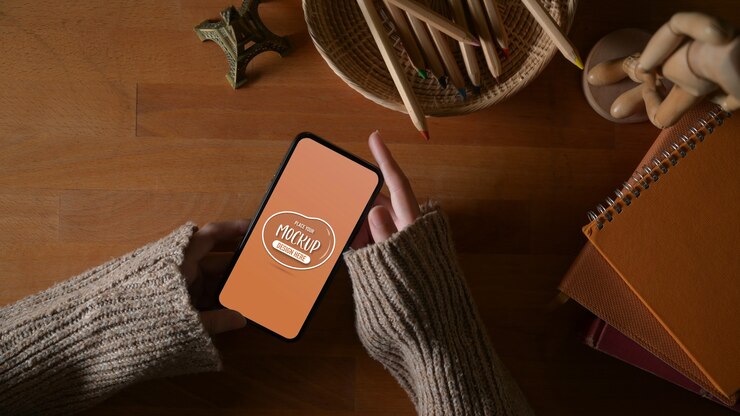 Photo 研究テーブルにスマートフォンをモックアップを保持している女性の手のオーバーヘッドショット