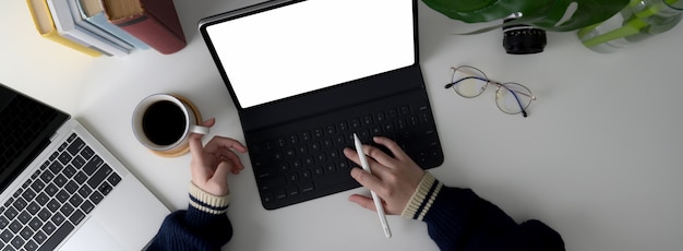 Overhead shot of female university student doing assignment with laptop and  tablet