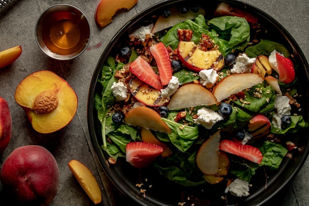 Scatto dall'alto di una sana insalata di frutta e verdura con cucchiai di crema di formaggio