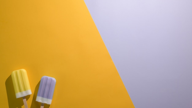 Overhead shot of lime and blueberry flavour popsicles and copy space on flat lay green and  purple background