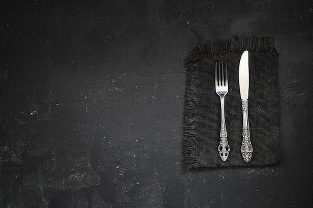 Overhead shot of silverware on black table with copy space