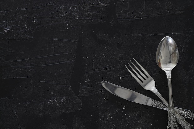 Overhead shot of silverware on black table with copy space