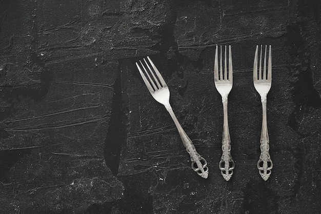 Overhead shot of silverware on black table with copy space