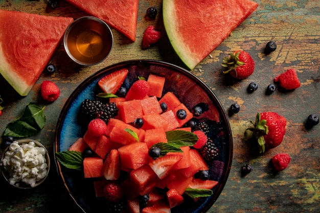 Overhead shot of sliced fresh watermelons with berries on a rustic, wooden table