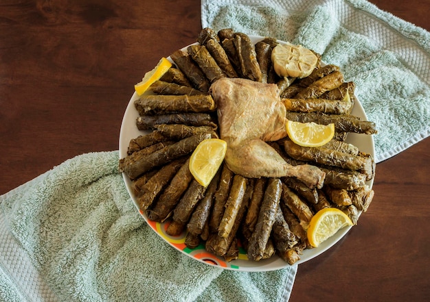 Overhead shot of a traditional Arabian meal of grape leaves with chicken meat served with lemons