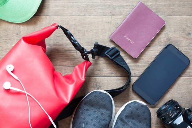 Foto overhead shot van reisartikelen en accessoires met mobiel apparaat op houten achtergrond, platte lay-out van zomer en vakantieartikelen