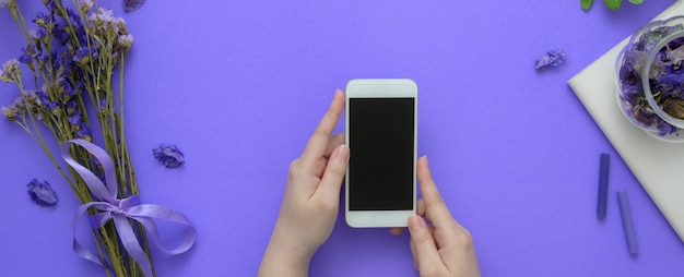 Overhead shot of a woman holding smartphone on purple table