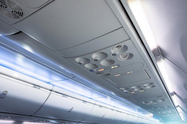 Overhead vents and lights along with luggage racks for hand luggage in an airplane.