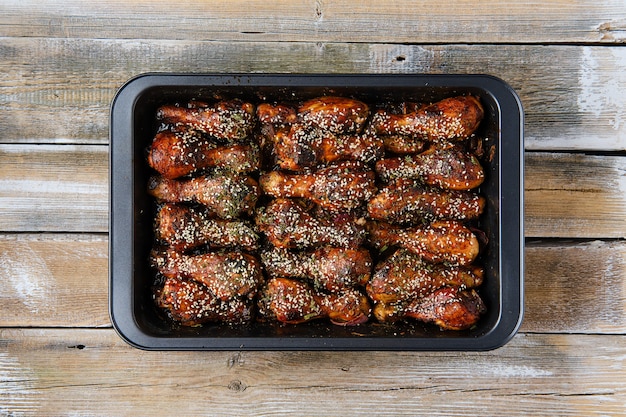 Overhead view of baked chicken legs with spicy sauce on a baking tray