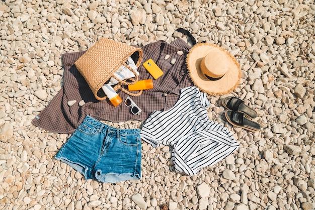 Overhead view of beach stuff blanket with sun protection cream straw hat with bag flat lay