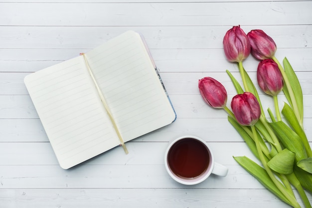 Overhead view of a bouquet of tulips and notebook and a Cup of coffee. 