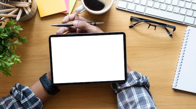 Overhead view of businessman hands using digital tablet on wooden office desk
