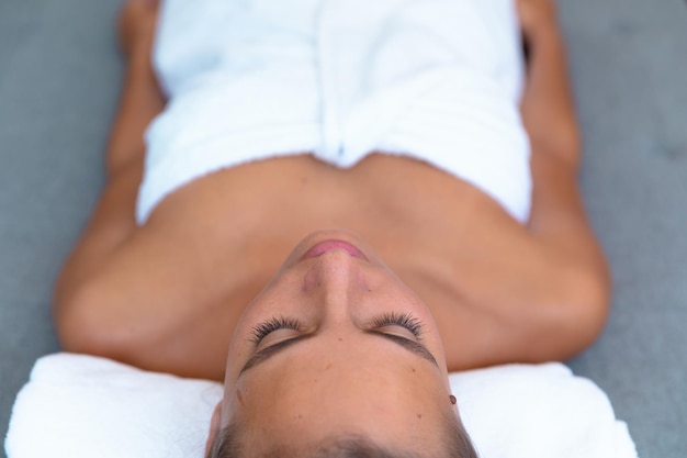 Photo overhead view of caucasian young woman in a bathrobe relaxing on the massage table. spa, wellness and relaxation concept