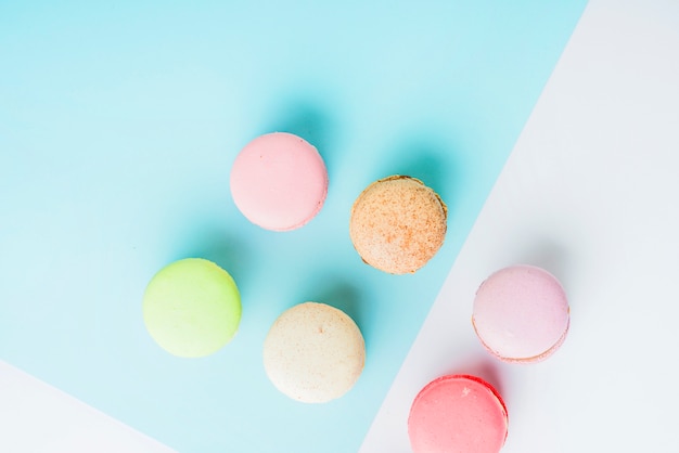 An overhead view of colorful macaroons on blue and white dual background