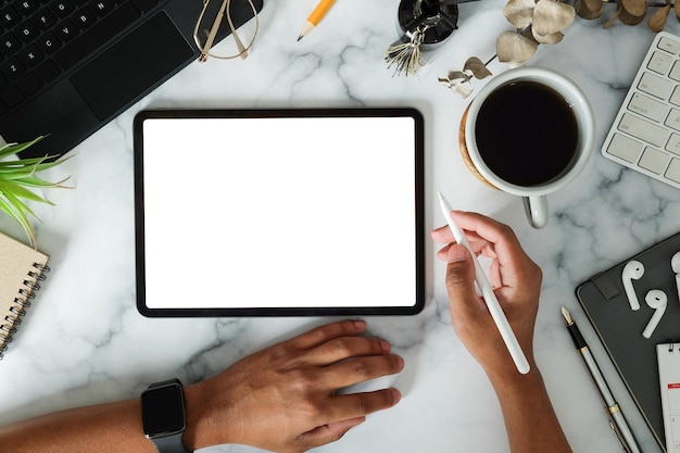 Vista dall'alto uomo creativo che tiene la penna stilo e utilizza la tavoletta digitale su un tavolo di marmo