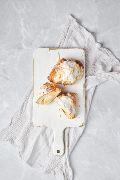 Overhead view of croissant with caramel and peanut shavings on wooden serving board