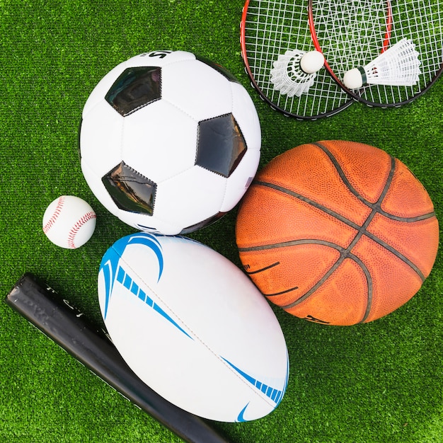 An overhead view of different type of sports equipment on green turf