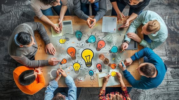 Overhead view of diverse team in brainstorming meeting with sketches of lightbulbs symbolizing ideas