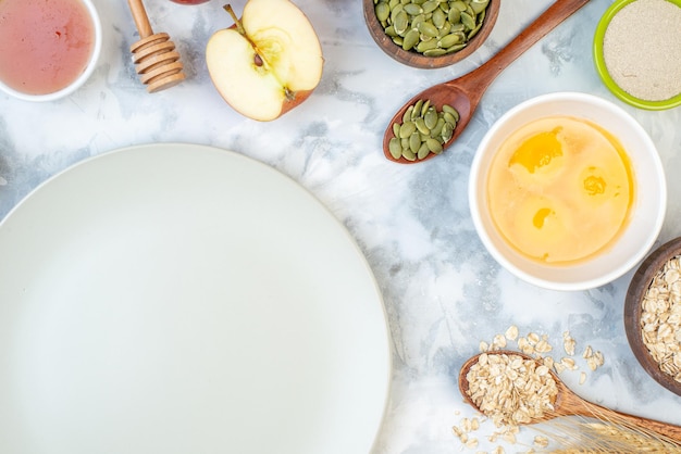 Overhead view of empty white plate and fresh healthy food set on ice background