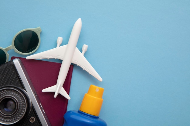 Overhead view of essential holiday travel items with a toy airplane on a blue background.