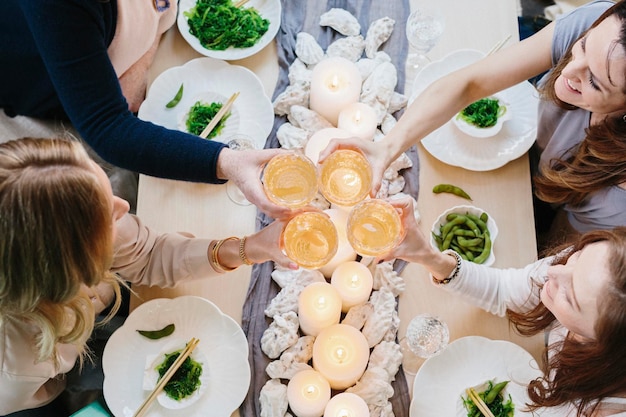 Photo overhead view of four people sharing a meal plates of sushi and a table setting for a celebration meal