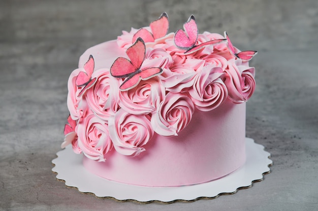 Overhead view of a freshly baked cake decorated with pink icing sugar roses displayed on a cake stand over a black background with copyspace.