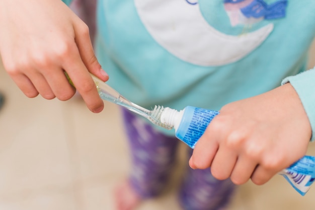 Overhead view of girl placing toothpaste on tooth brush