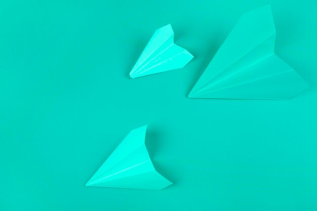 overhead view green paper airplanes mint background