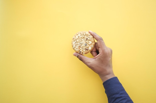 Photo overhead view of holding sweet cookies on yellow background