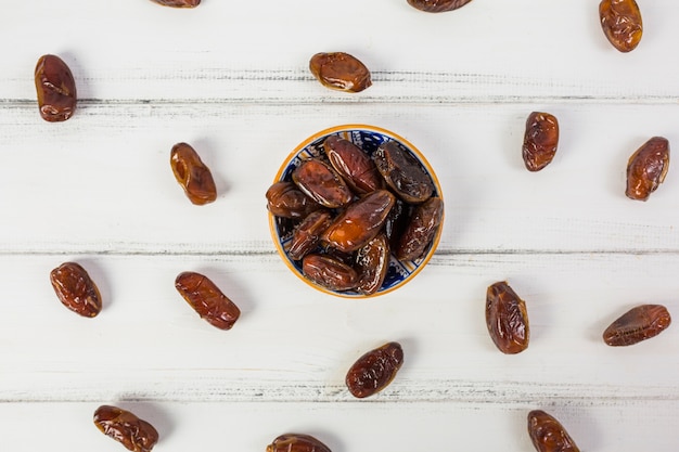 An overhead view of juicy ripe dates bowl over the white desk