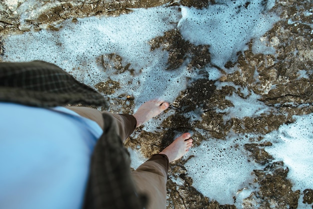 Overhead view man barefoot walking by sea rocky beach