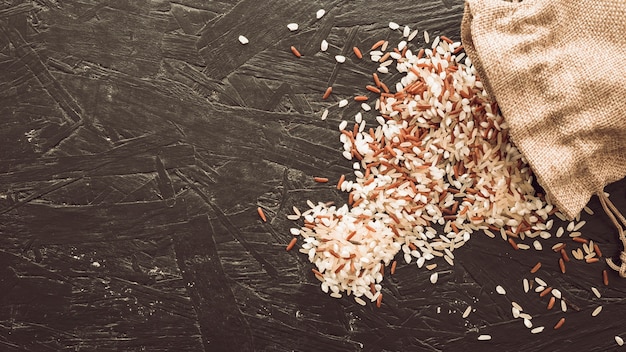 Фото Верхний вид смешанных рисовых зерен, разлитых из мешка