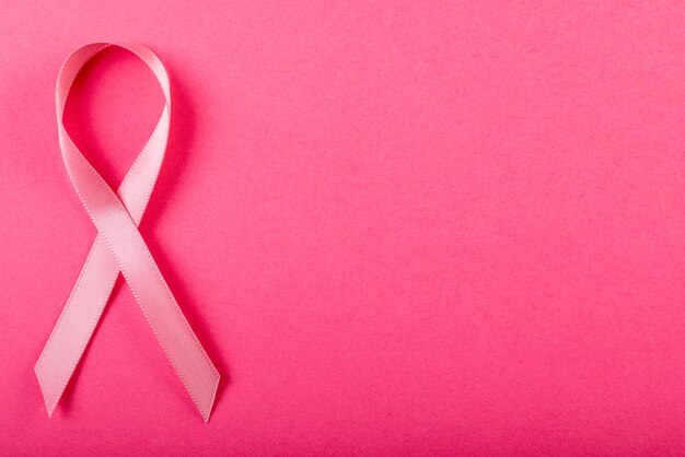 写真 ピンクの背景に分離されたピンクの乳がん啓発リボンのオーバーヘッドビュー。コピースペース。ピンク、乳房、がん、医療、リボン、意識、サポート、ヘルスケア、警戒のコンセプト。