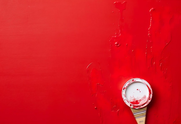 Overhead view of a paintbrush and a tin of red paint