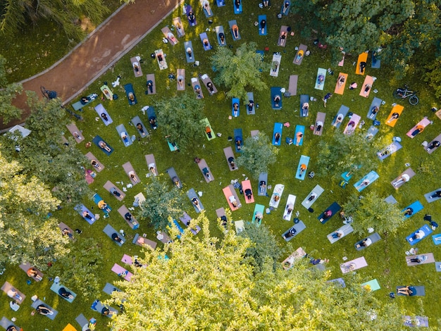 Вид сверху на людей, занимающихся йогой в городском общественном парке