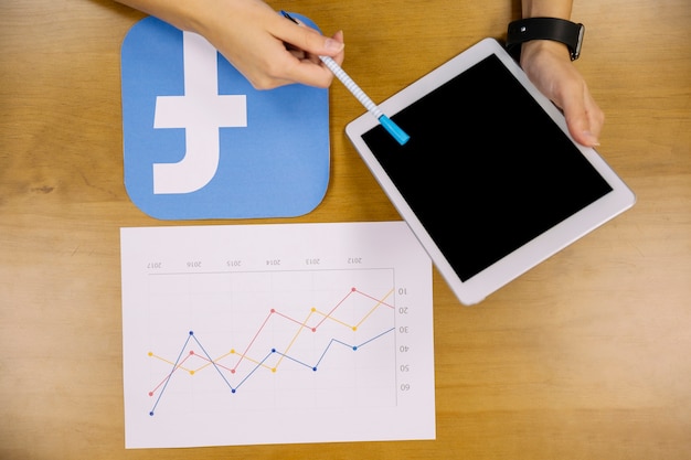 Overhead view of a person holding digital tablet analyzing facebook graph