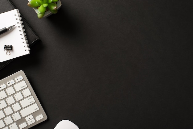 Overhead above view photo of stylish trendy work space with succulent diary notebook with paperclip keyboard and mouse isolated black backdrop with blank empty place