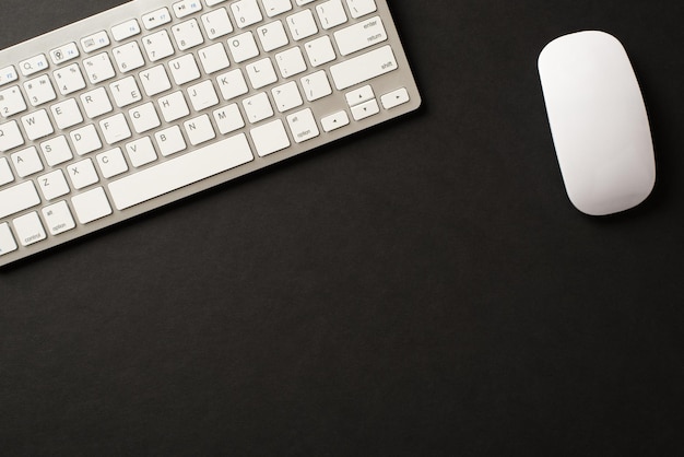 空白のスペースで白い色の孤立した黒い背景のワイヤレスキーボードとマウスの俯瞰写真の上