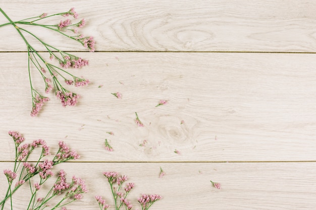 An overhead view of pink limonium flowers on wooden textured surface