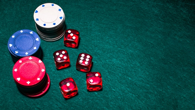 Photo overhead view of red dices and casino chip stacks on green poker table