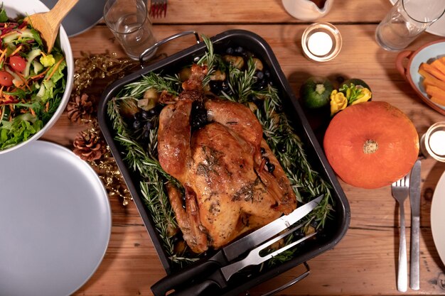 Overhead view of roast turkey, salad, vegetables, plates and candles on the Thanksgiving dinner table at home