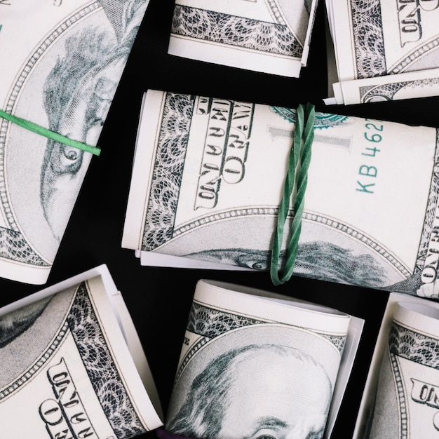 An overhead view of rolled up us dollar currency note on black background